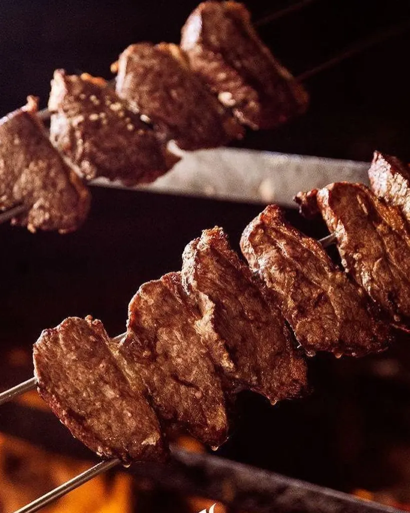 Espetos de picanha assando sobre a brasa